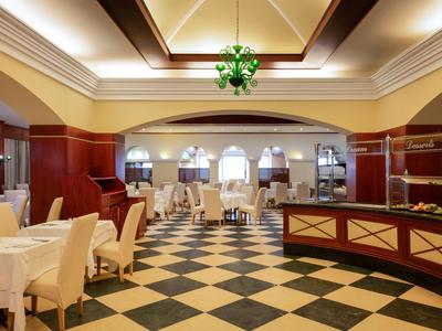 Eleganter Hotel-Diningraum mit schwarz-weiß kariertem Boden und cremefarbenen Tischdecken.