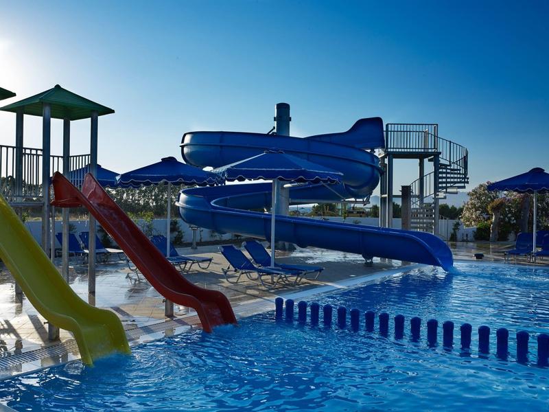 Wasserrutsche mit blauen Spiralen und bunten geraden Rutschen neben einem Schwimmbecken im Freien.