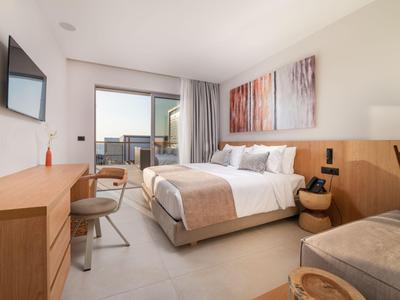Modernes Hotelzimmer mit Doppelbett, Flachbildschirm und Balkon mit Ausblick.
