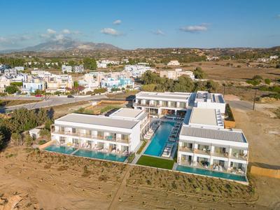 Nowoczesny kompleks hotelowy z basenem i tarasami w suchym, wiejskim otoczeniu pod niebieskim niebem.