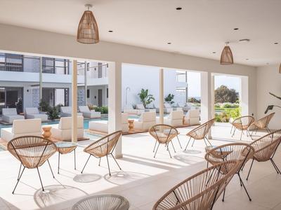 Heller, moderner Innenraum mit Korbstühlen und Blick auf einen Pool und Außenbereich.