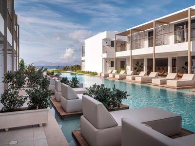 Moderner Hotelpool mit Liegestühlen und Sitzbereichen unter blauem Himmel.