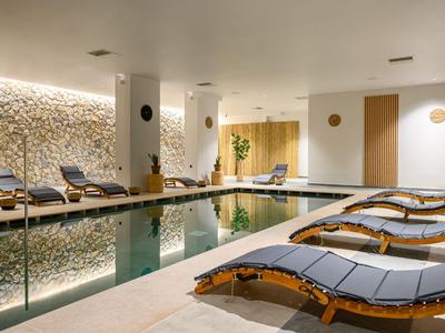 Moderner Wellnessbereich mit Innenpool, Liegen und entspannter Atmosphäre.
