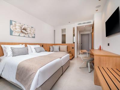 Nowoczesny pokój hotelowy z łóżkiem podwójnym, telewizorem i drewnianymi meblami.