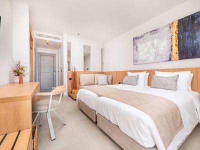 Nowoczesny pokój hotelowy z łóżkiem podwójnym, biurkiem, krzesłem i współczesną sztuką na ścianie.