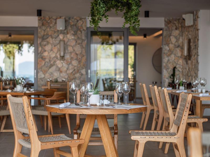 Nowoczesna restauracja z drewnianymi meblami i elegancko nakrytymi stołami w świetle dziennym.