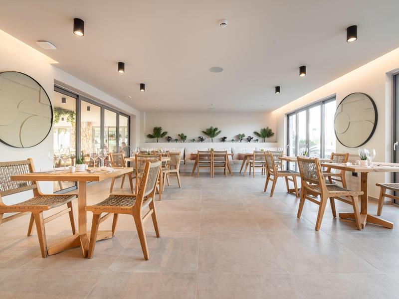 Jasna, nowoczesna restauracja z drewnianymi meblami i dużymi oknami, zapewniająca dużo światła dziennego.