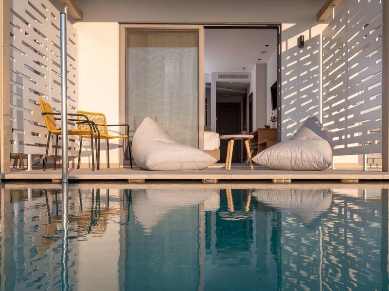 Nowoczesny teren z workami do siedzenia i krzesłami obok basenu o zachodzie słońca.