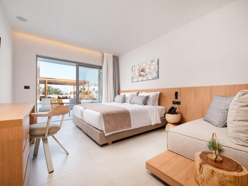 Nowoczesny pokój hotelowy z podwójnym łóżkiem, sofą, telewizorem i biurkiem z krzesłem.