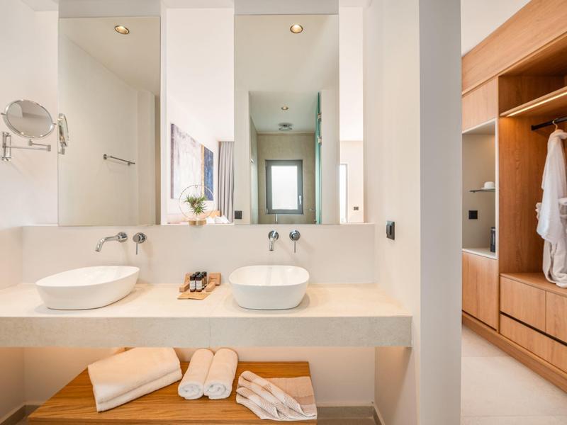 Nowoczesna łazienka z dwiema umywalkami, dużymi lustrami i drewnianą szafką z szlafrokami.