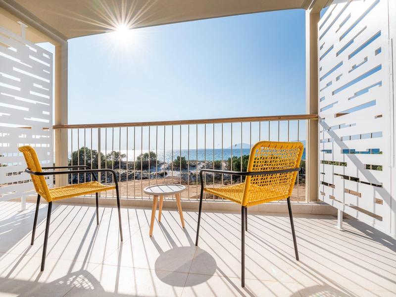 Balkon z żółtymi krzesłami i widokiem na morze w słoneczny dzień