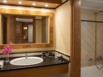 Moderní hotelová koupelna s umyvadlem, zrcadlem, květinami a vanou.