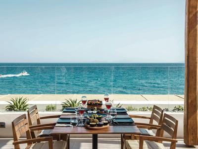 Terrassentisch mit gedeckten Gläsern und blauem Meer im Hintergrund.