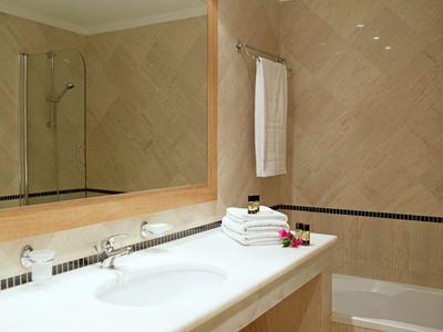 Helles Hotel-Badezimmer mit Waschbecken, großen Spiegeln und gefliesten Wänden.