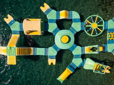 Bunter schwimmender Wasserspielplatz mit Rutschen und Hindernissen auf glattem Wasser.
