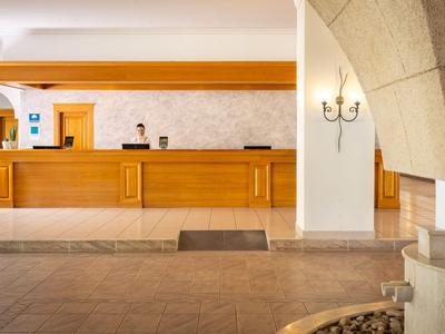 Hotelrezeption mit hölzernem Empfangstresen und heller Wandgestaltung.