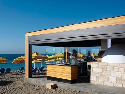 Moderner Strandpavillon mit gelben Sonnenschirmen und Blick auf das Meer bei klarem Himmel.