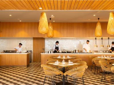 Modernes Buffetrestaurant mit Holztischgruppen und gelben Hängeleuchten in warmem Ambiente.