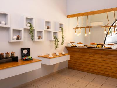 Modernes Bistro mit hölzernem Tresen, Wandregalen und dekorativen Pflanzen.