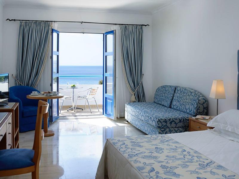 Hotelový pokoj s výhledem na moře, postel, pohovka a balkón s výhledem na oceán.