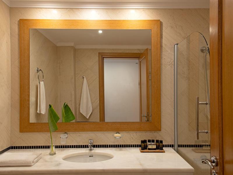 Koupelna s velkým zrcadlem, dvěma umyvadly a držáky na ručníky, v neutrálních barvách a moderním vybavením.