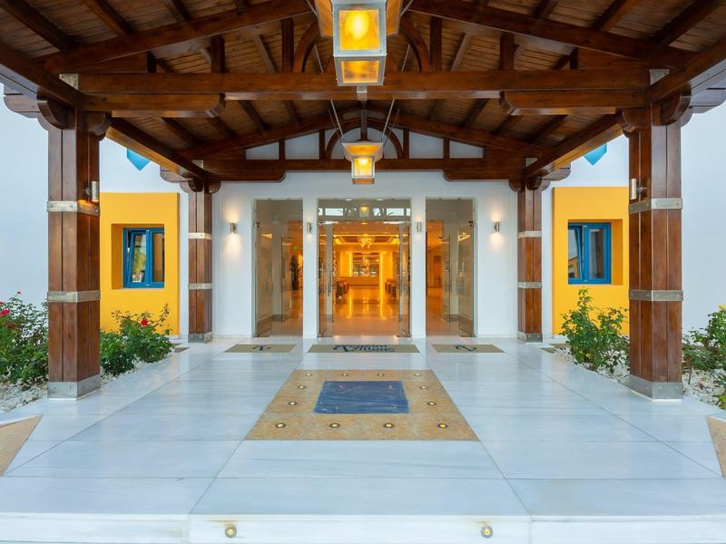 Vstup do hotelu s krytou dřevěnou střechou a dekorativními rostlinami.