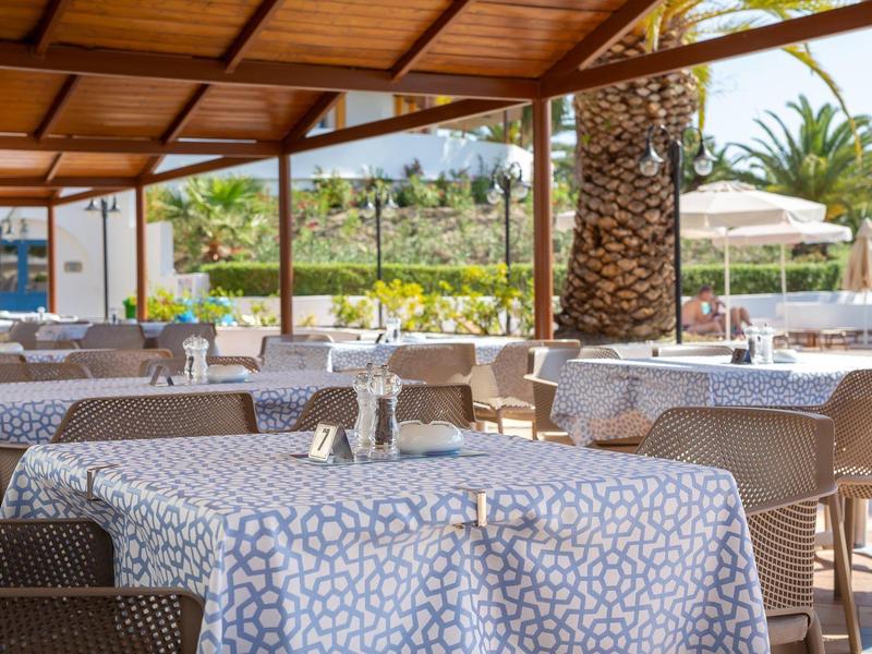 Zastřešená venkovní část hotelu s řadami stolů a vzorovanými ubrusy.