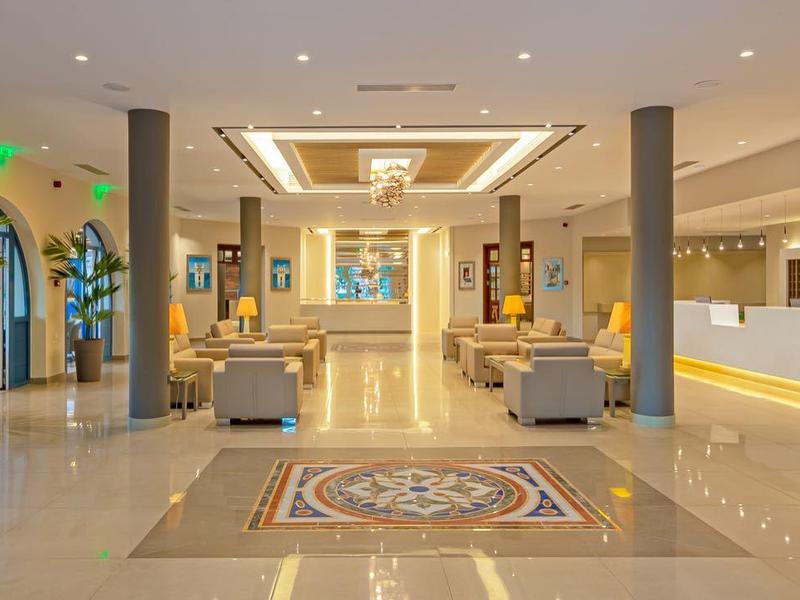 Prostorná hotelová lobby s jasným osvětlením, elegantními sloupy a recepcí.
