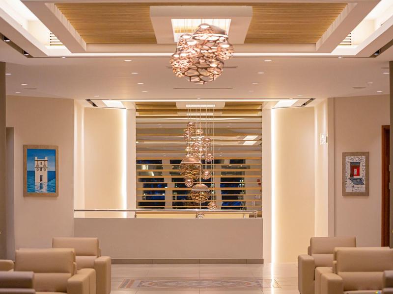 Moderní interiér hotelové lobby s pohodlnými pohovkami a dekorativními lustry.