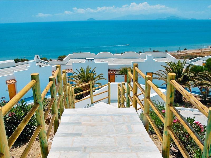 Schodiště s zábradlím, palmami a výhledem na moře v rekreačním středisku.