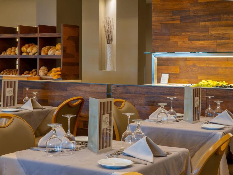 Elegantní restaurace s prostřenými stoly a dřevěnými policemi plnými čerstvého chleba.