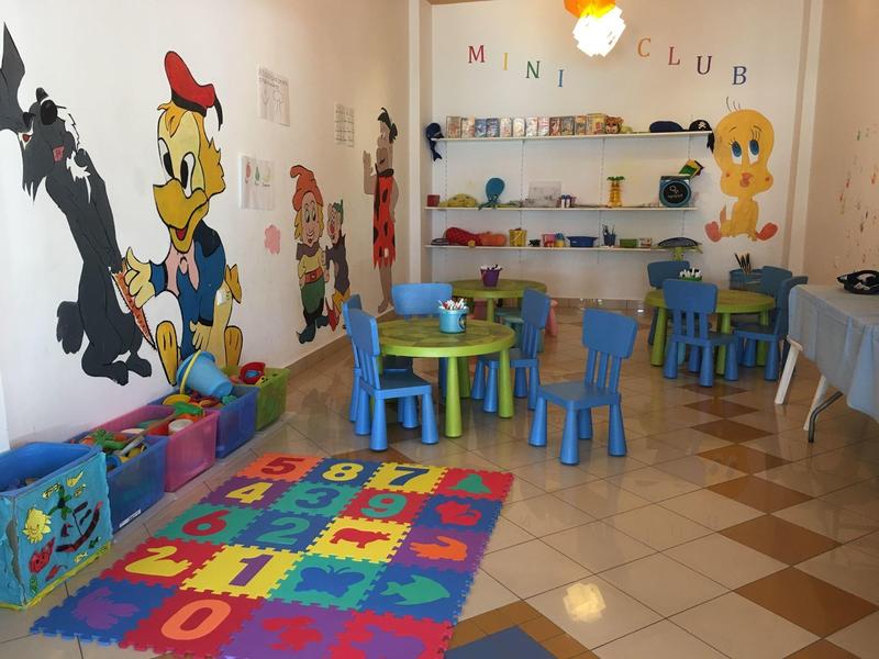 Dětský pokoj s barevnými židlemi, hračkami a nástěnnými malbami kreslených postaviček.