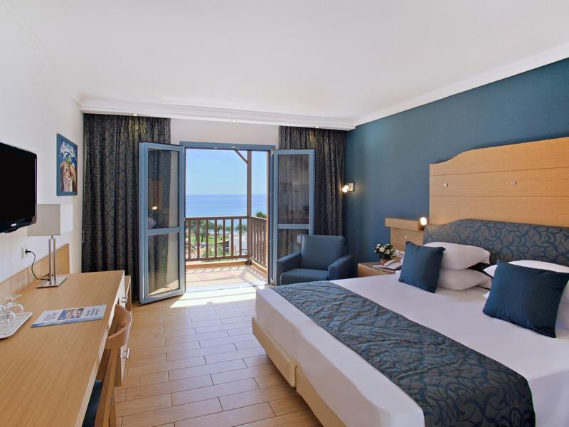 Moderní hotelový pokoj s manželskou postelí, balkonem a výhledem na moře.