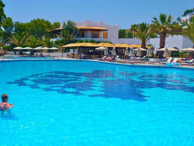 Velký venkovní bazén s slunečníky a lehátky za slunečného dne v hotelu.