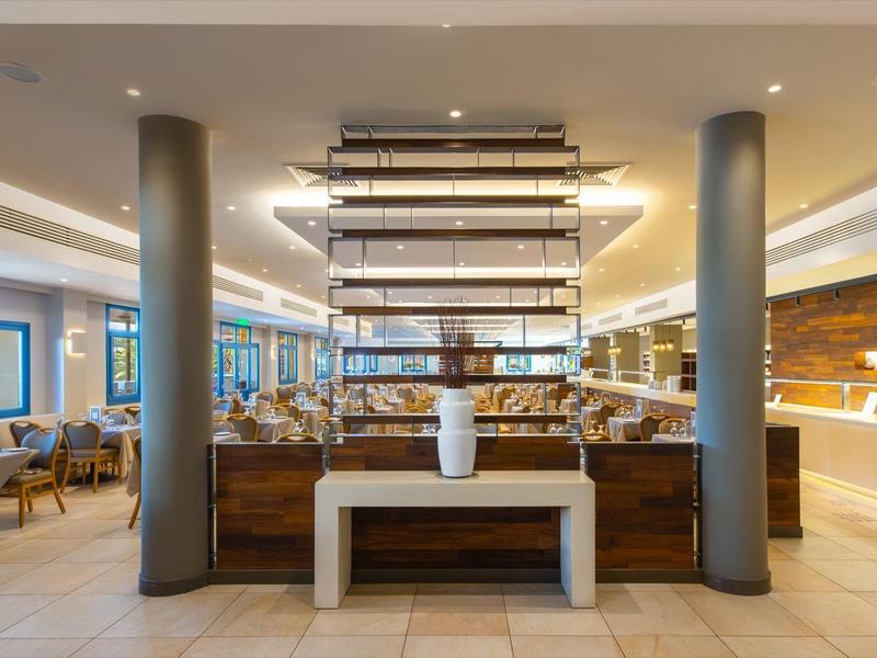 Moderní, světlá hotelová restaurace s bufetem a sezením u okna.