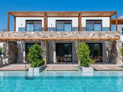 Modern vakantiehuis met stenen muren en groot zwembad ervoor.