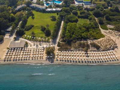 Vogelperspektive auf einen Hotelstrand mit Reihen von Sonnenschirmen und Liegen neben klarem Wasser.