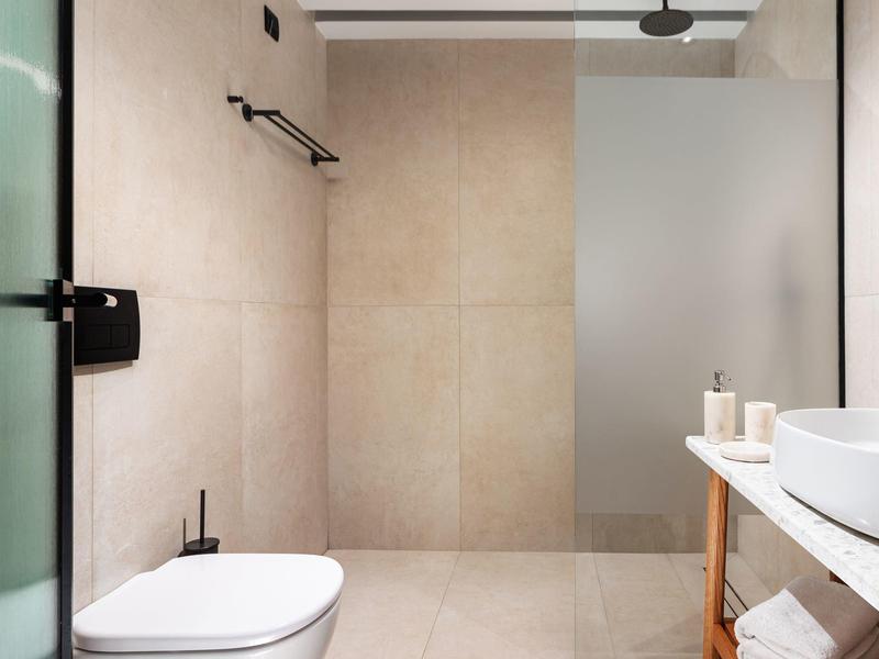 Minimalistische badkamer met wandtoilet en inloopdouche met matglazen scheidingswand.