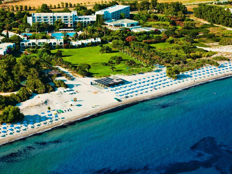 Strandresort met witte parasols, helderblauwe zee en weelderige groene omgeving