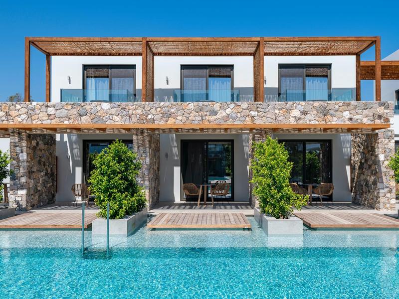 Modern vakantiehuis met stenen muren en groot zwembad ervoor.