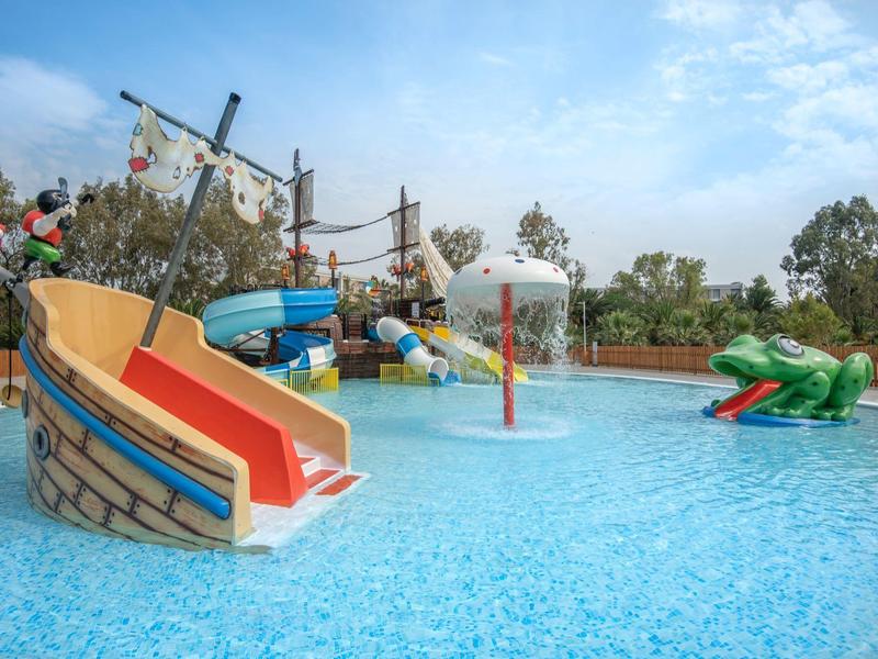 Kleurrijke waterspeeltuin met glijbanen en waterelementen onder een deels bewolkte lucht