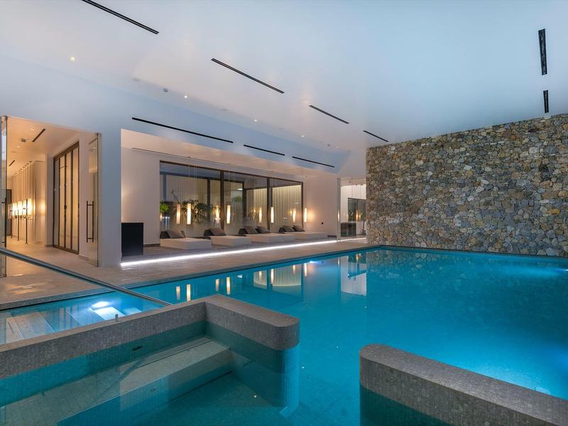 Overdekt zwembad met moderne verlichting en stenen accentmuur in een luxe hotel.