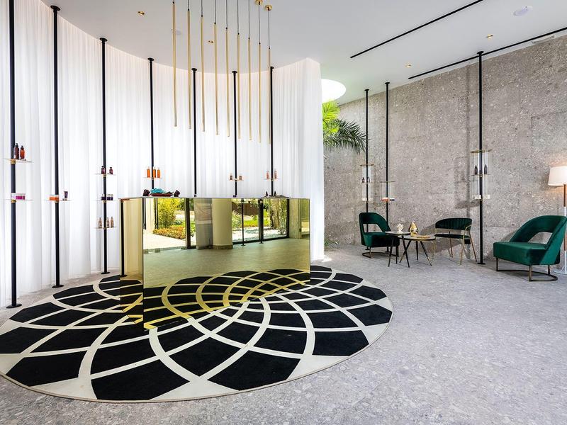 Moderne hotel lobby met een stijlvolle zwart-witte ronde vloerkleed, fluwelen stoelen en gouden receptiebalie.