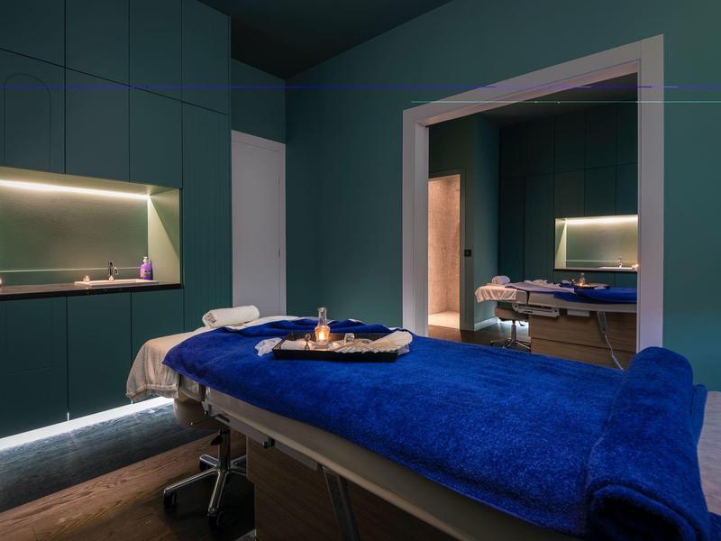 Gezellige spa ruimte met massagetafels en zachte blauwe handdoeken bij warm licht.