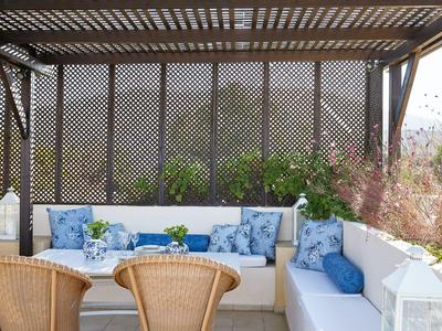 Cozy outdoor seating area with blue cushions and wicker chairs under a wooden pergola.
