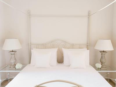Light, airy bedroom with a white four-poster bed, white pillows, and matching bedside lamps.