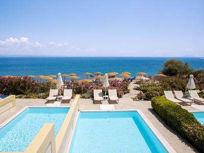 Luxury pool area with sunbeds overlooking a clear blue sea and bright sky