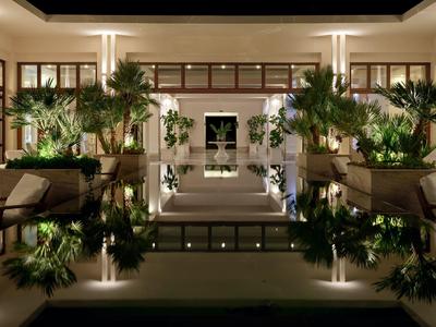Elegant hotel lobby with plants and reflections on shiny floor.