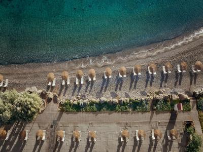 Aerial view of a beach with evenly arranged sun umbrellas and lounge chairs.