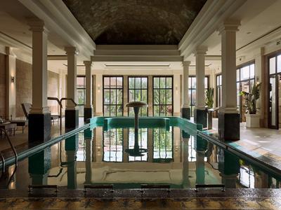 Luxurious indoor pool with columns and large windows in elegant hotel area.